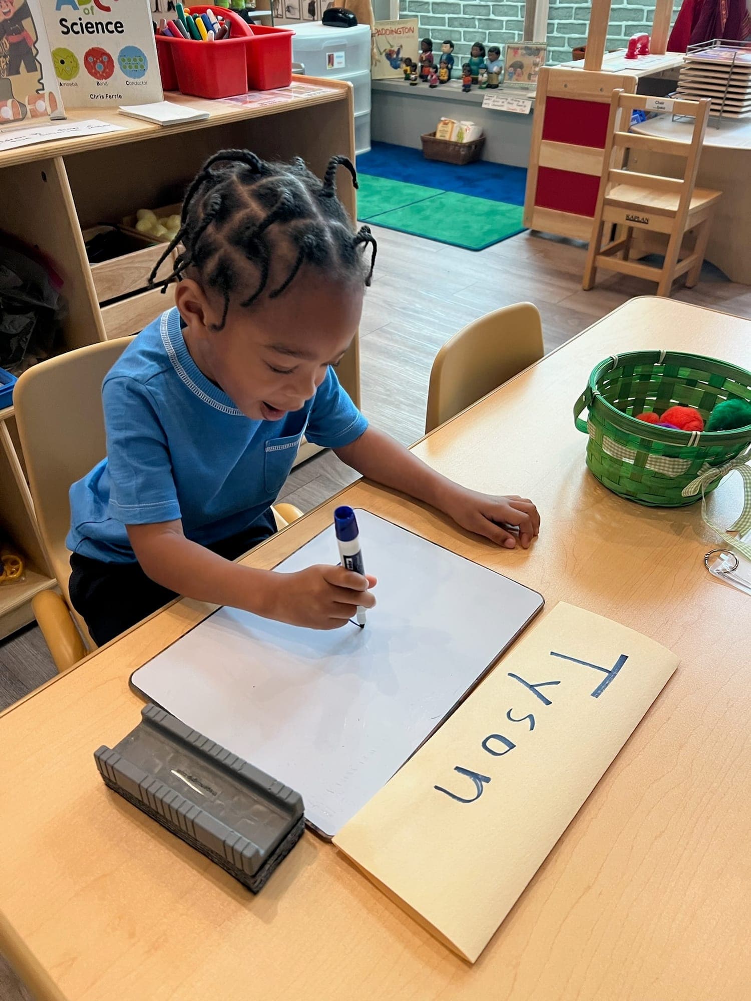 Boy practicing letter formation with classroom materials