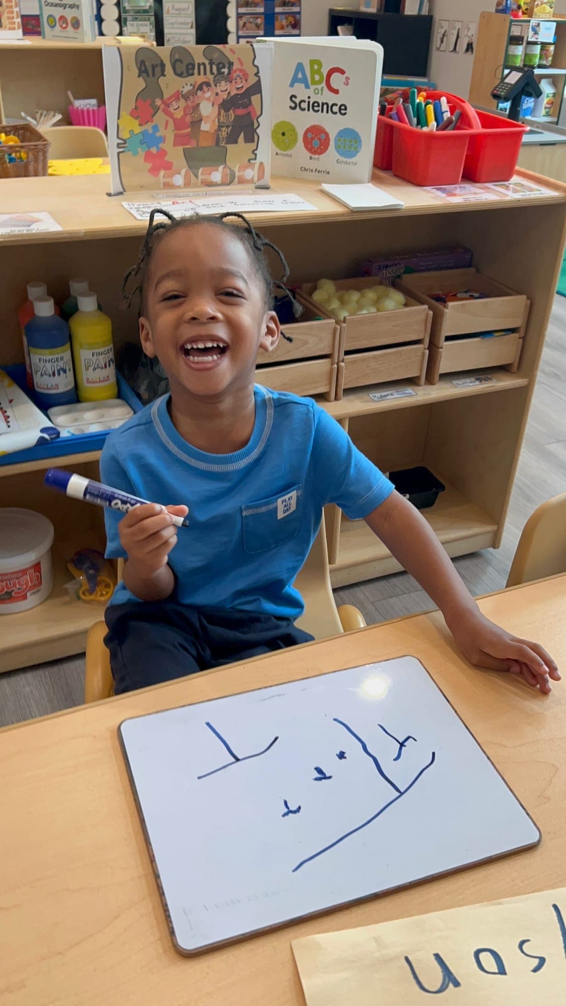 Child explaining a number activity at a classroom table