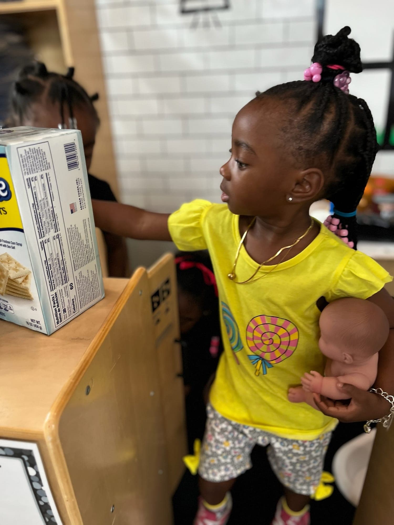Sprouts child caring for a doll during dramatic play
